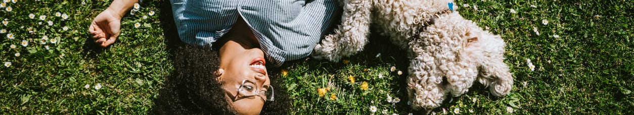 woman laying on grass with dog
